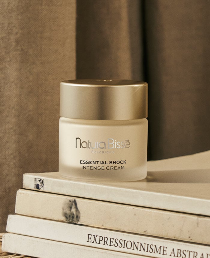 Essential Shock Intense Cream sobre una pila de libros